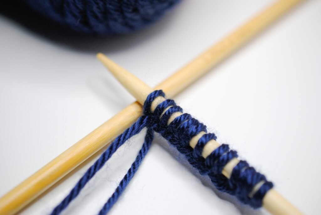 2 knitting needles with blue yarn on them. Learn a new skill together