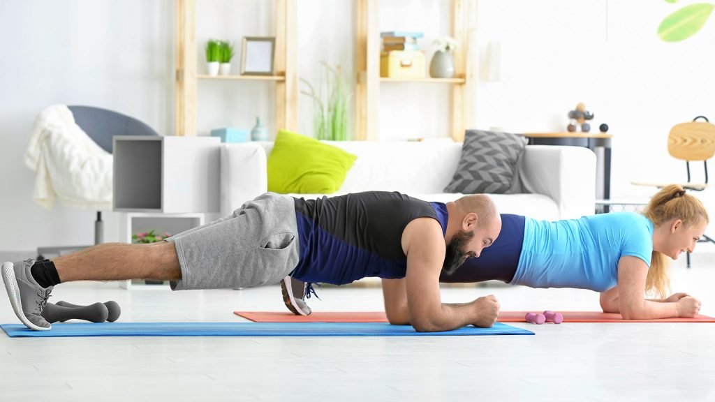 2 people a man and a women in the plank position wearing workout clothes. At home workout challenge