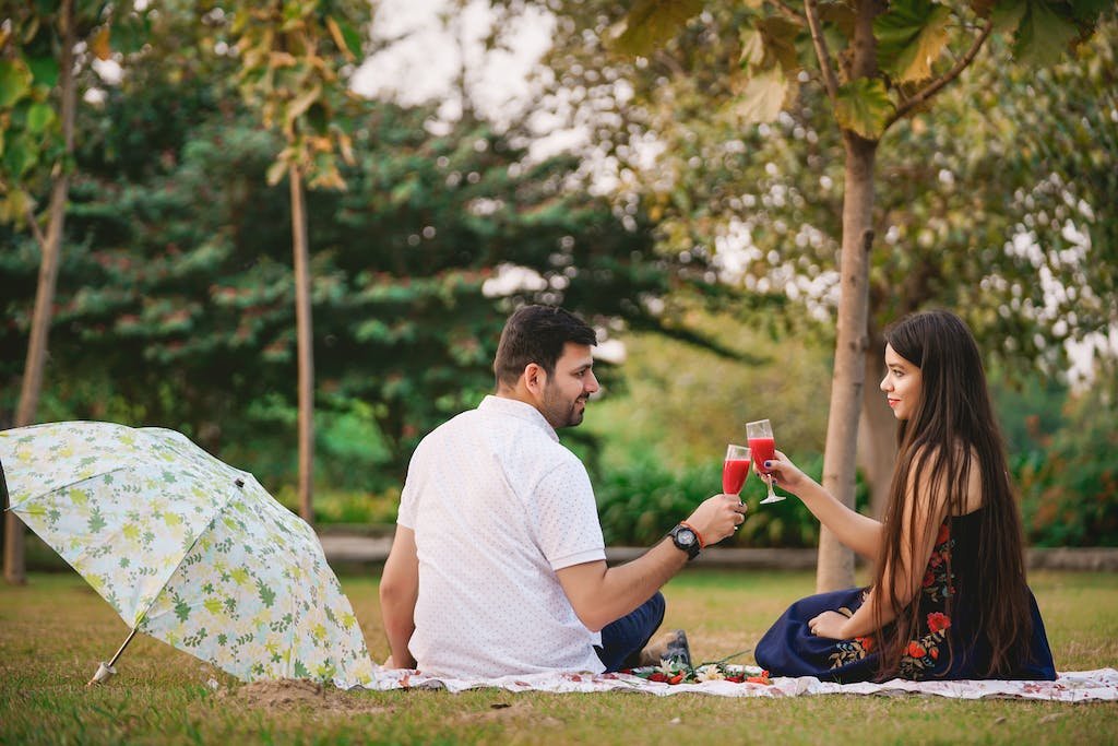 Man In White Collared Shirt Sitting On Ground With Woman In Blue Sleeveless Dress budget date night when traveling