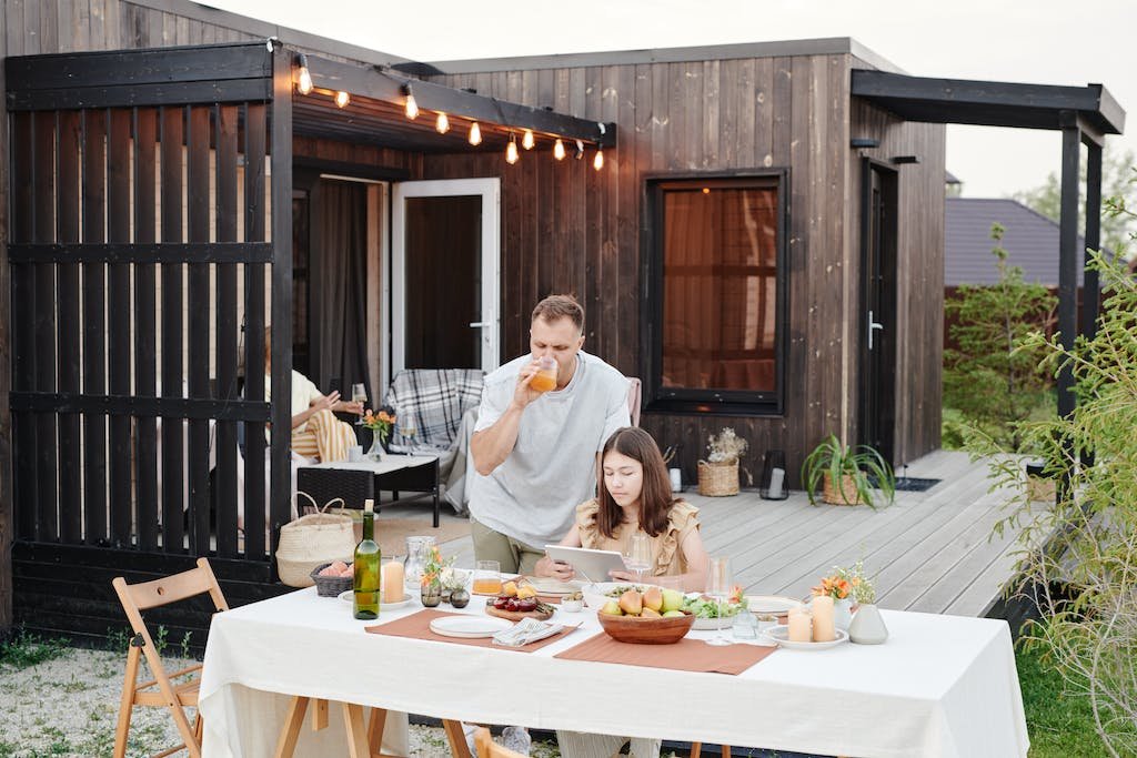 Man Standing Beside the Woman Sitting at Table for a backyard dinner date