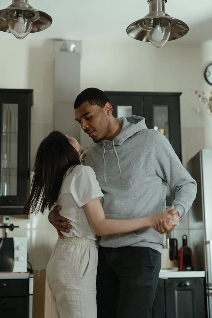 Man in Gray Hoodie Kissing Woman in White Dress