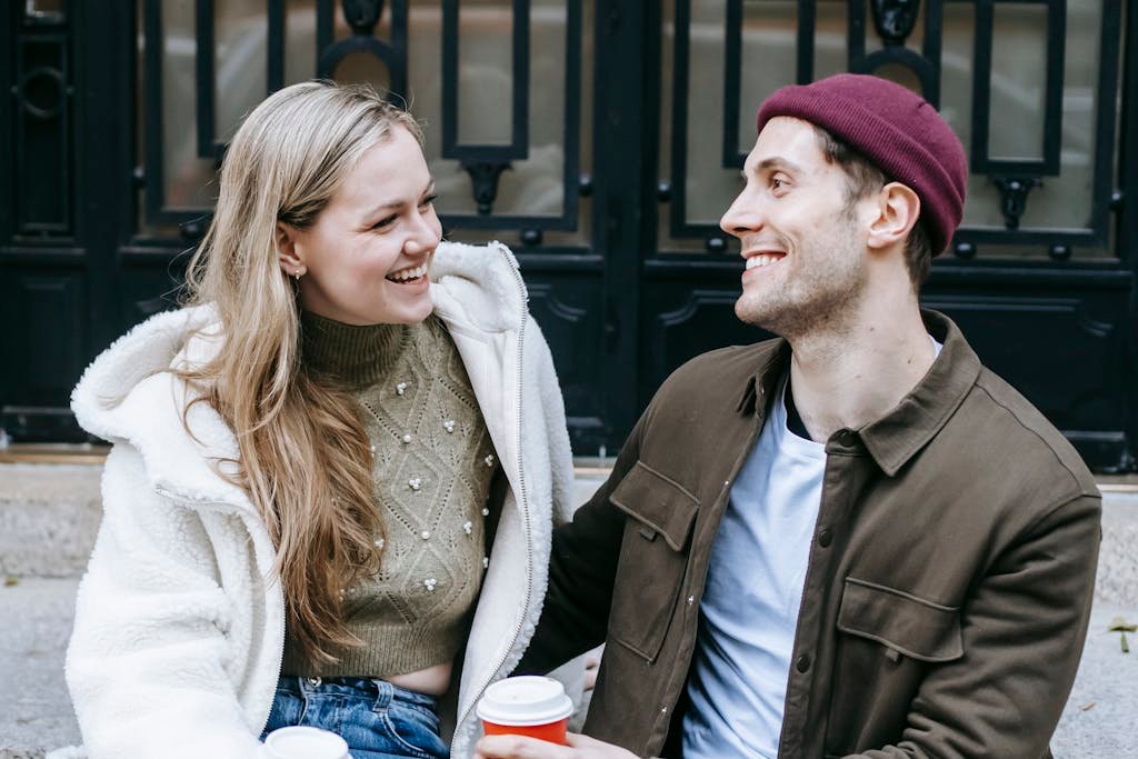 Happy young man and woman drinking coffee near big building