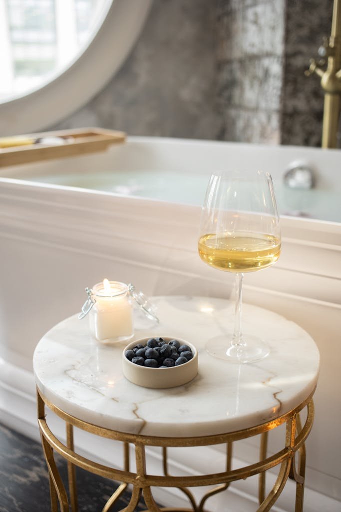 Round table with wineglass burning candle and berries in bathroom