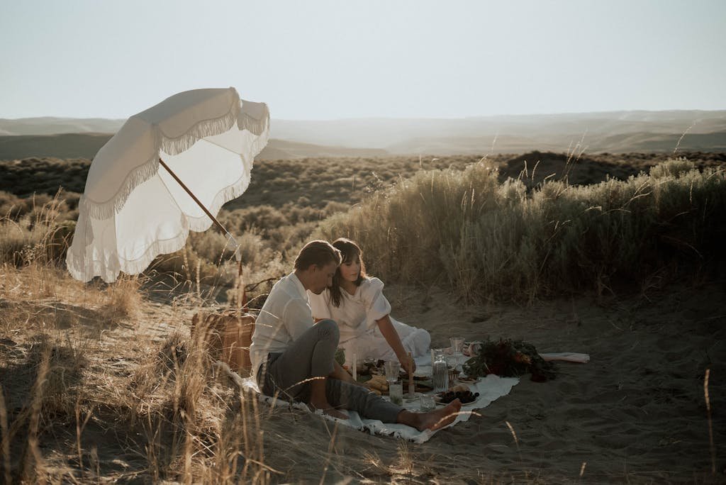 Young romantic couple having picnic on sandy beach during a mini-vacation date