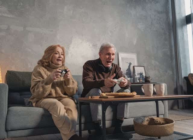 Man in Black Sweater Sitting Beside Woman in Brown Sweater playing video games