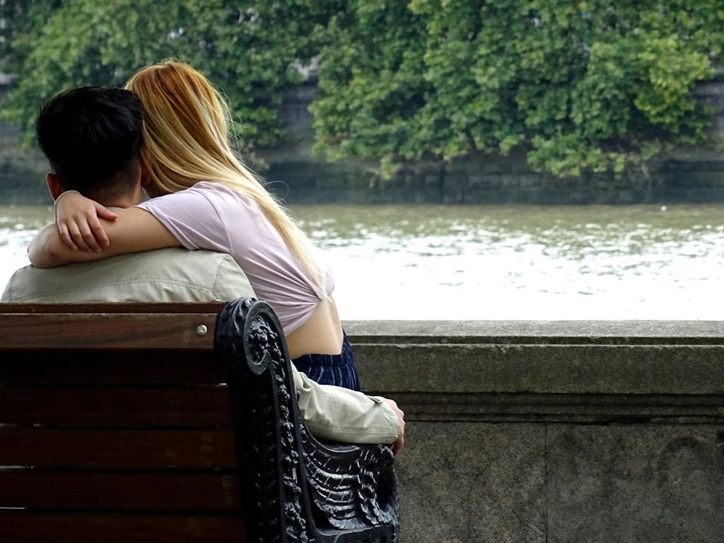 Man and Woman Sitting on Bench With River View