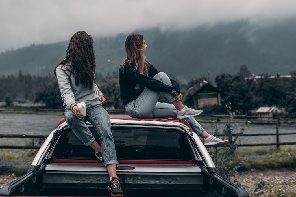 Two Women Sitting on Vehicle Roofs