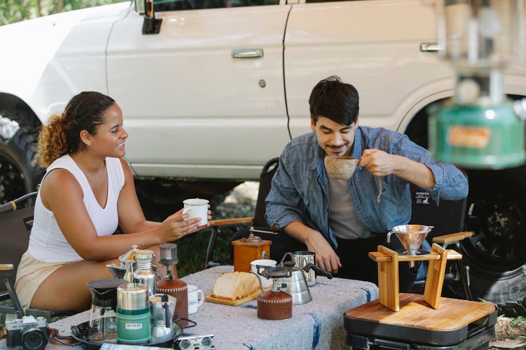 Positive diverse couple drinking delicious pour over coffee in campsite