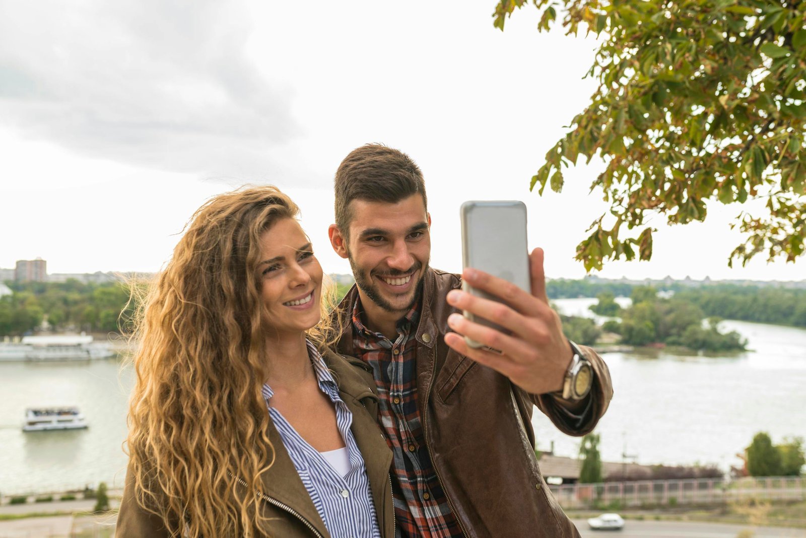 Man Holding Smartphone Beside Woman Near Tree