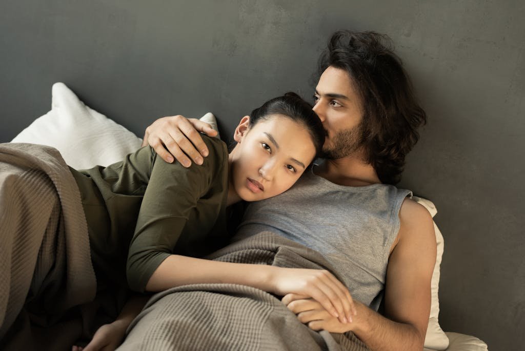 Woman in Green Top Lying on a Man's Chest in Bed