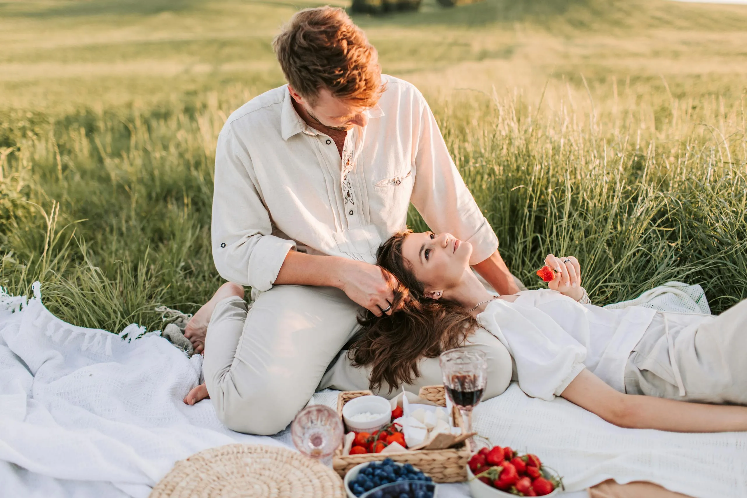 A Woman Lying on Her Partners Lap while Sitting on Picnic Blanket