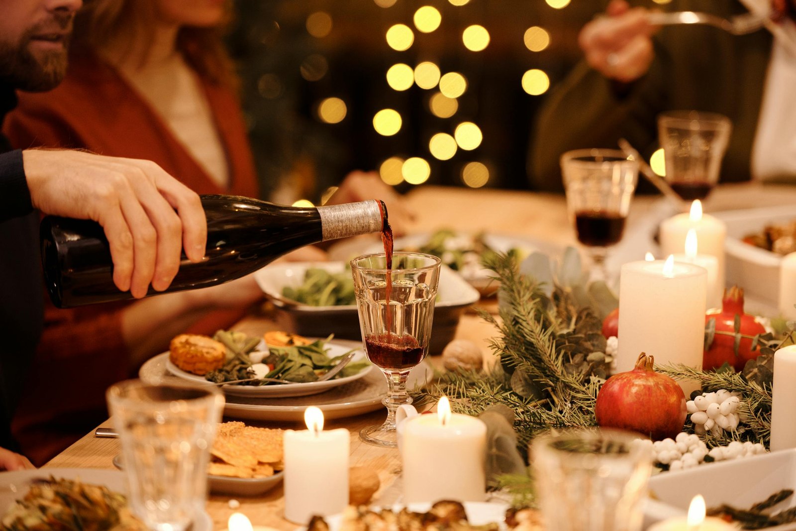 Warm holiday dinner setting with festive decorations, candles, and wine pouring for a joyful celebration.