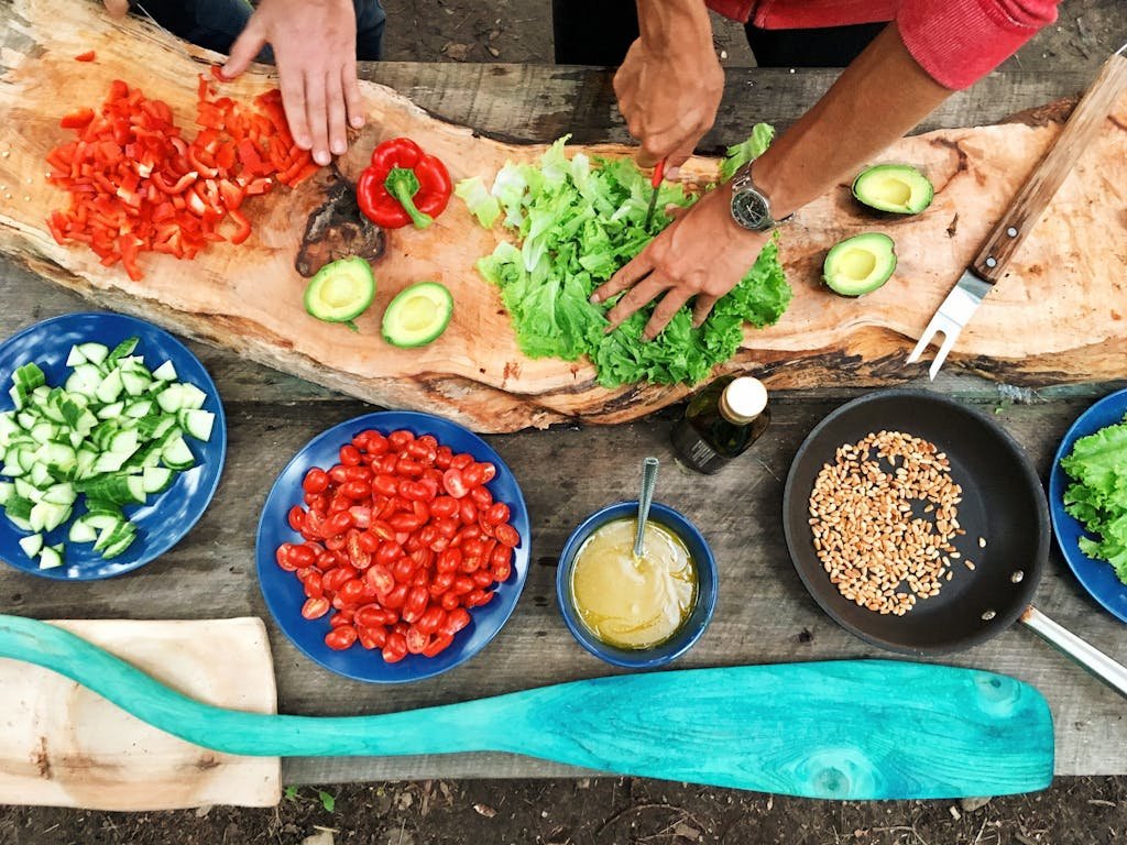 Fresh ingredients being prepared on a rustic wooden table, showcasing vibrant vegetables and hands at work for a Valentine's Day cooking class