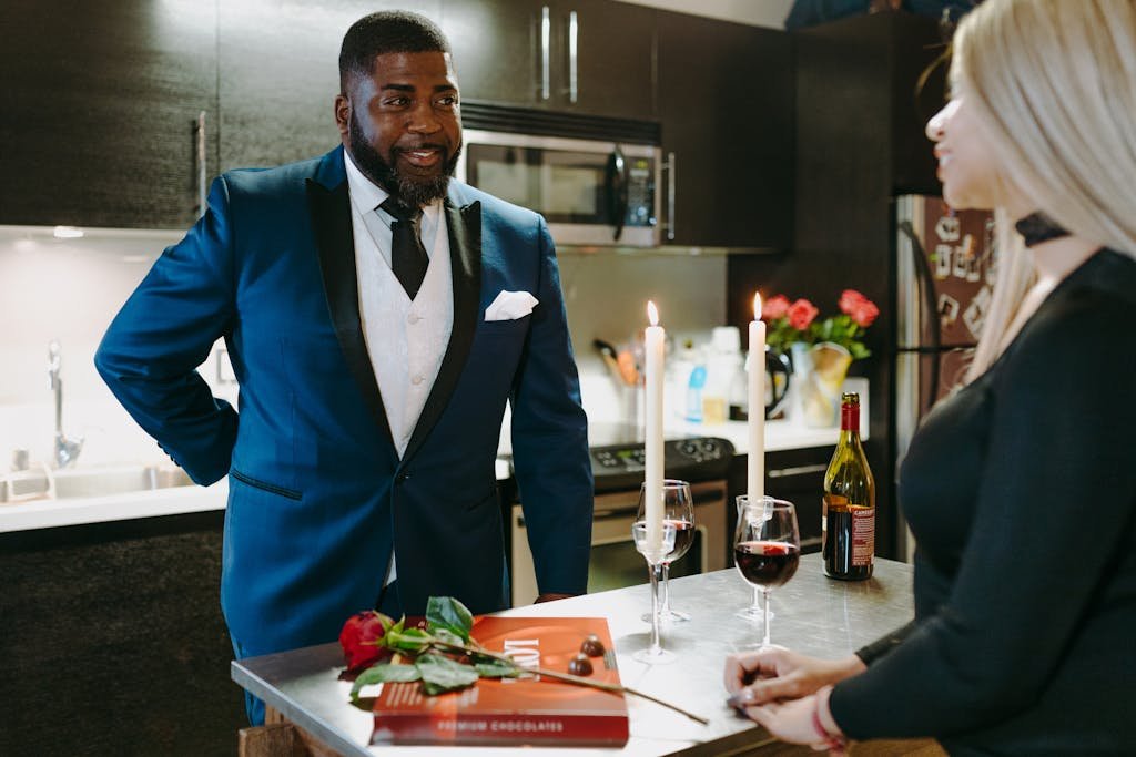 A couple enjoying a romantic dinner with candlelight and wine in a modern kitchen.