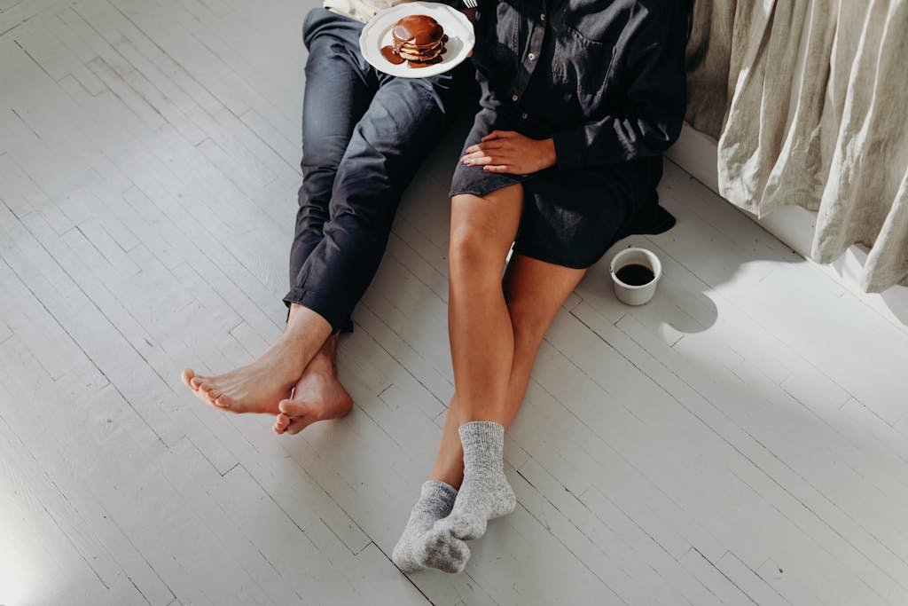 A cozy couple enjoying a quiet breakfast with pancakes and coffee on a sunlit floor.