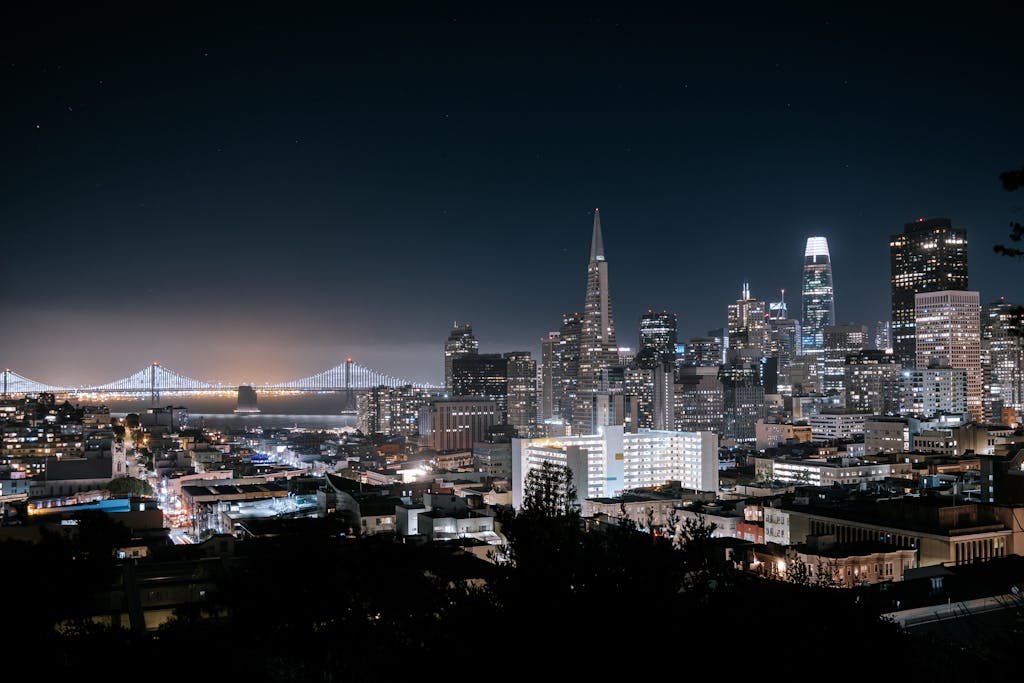 A stunning aerial view of San Francisco's skyline at night featuring the Bay Bridge and iconic skyscrapers.