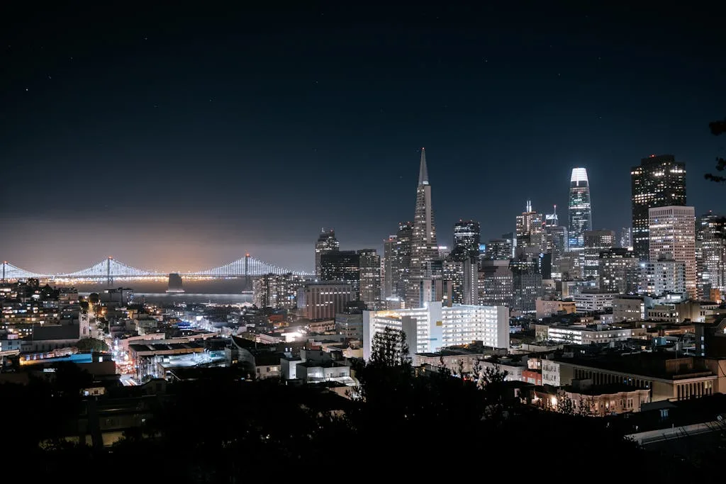 A stunning aerial view of San Francisco's skyline at night featuring the Bay Bridge and iconic skyscrapers.