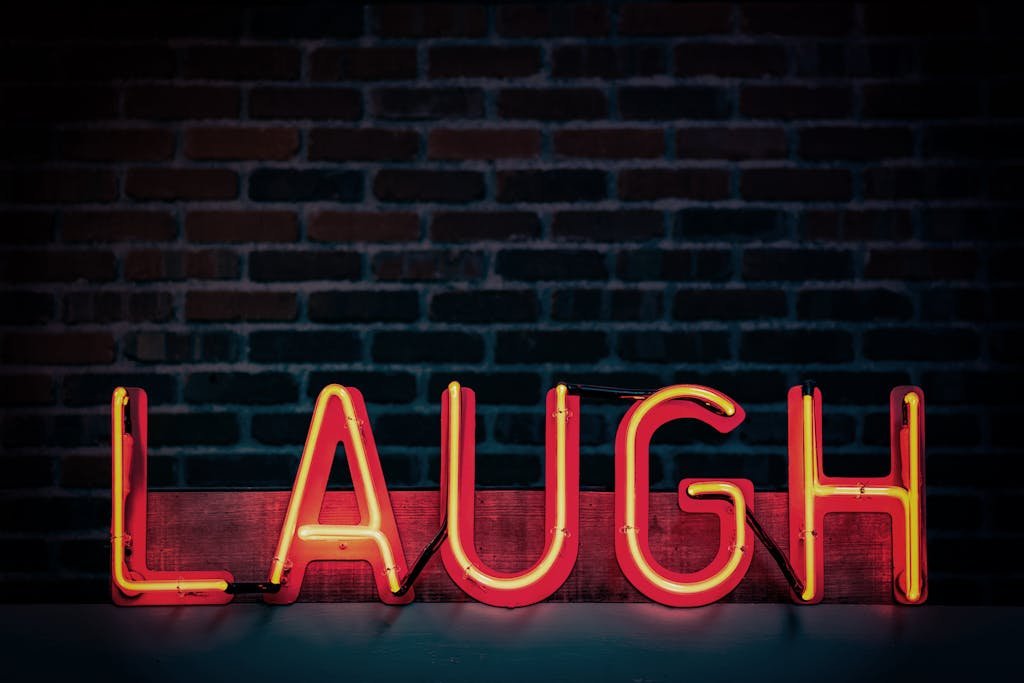 Bright neon sign displaying 'LAUGH' against a dark brick wall, creating a vibrant mood.