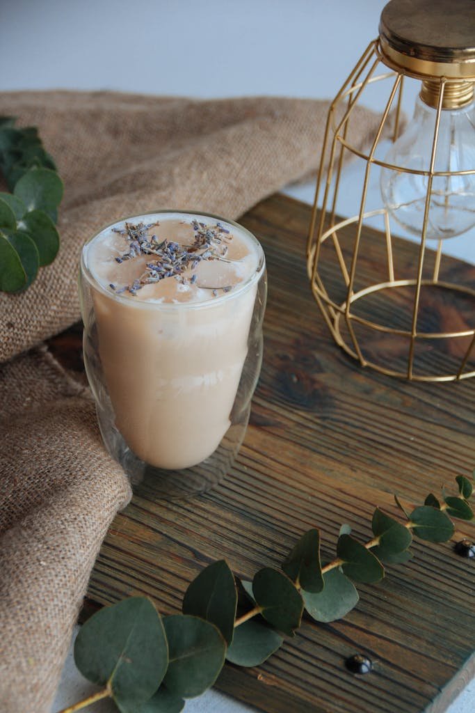 Chilled iced lavender latte with ice cubes on a wooden cutting board.