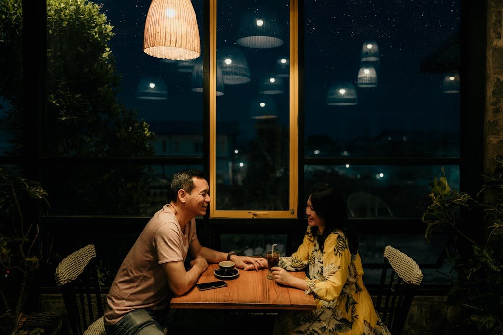 Couple enjoying a romantic evening at a restaurant under warm lighting.