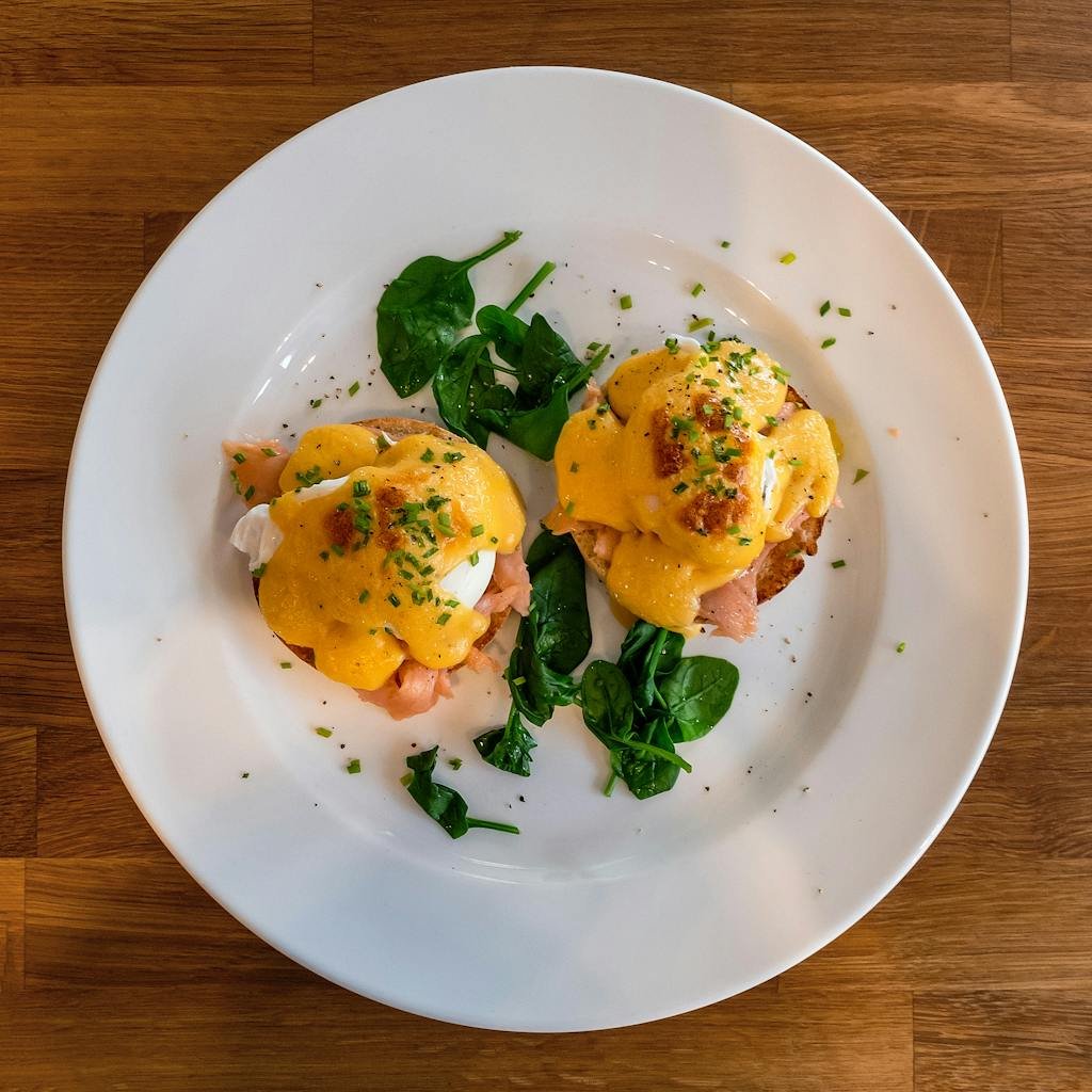 Delicious Eggs Benedict with spinach on a white plate perfect for breakfast or brunch.