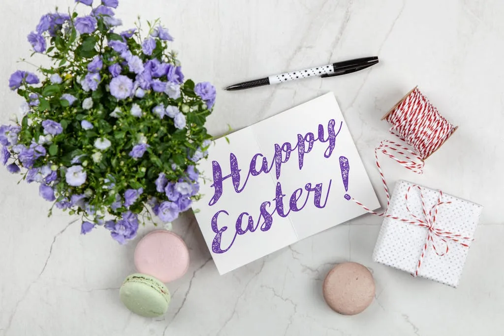 Easter greeting card with flowers, macarons, and gift on a marble surface.