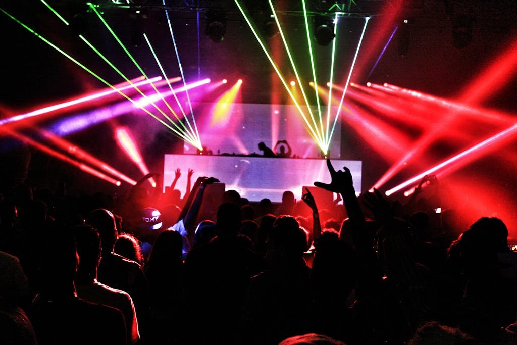 Energetic nightclub scene with laser lights and a lively crowd dancing to EDM music.