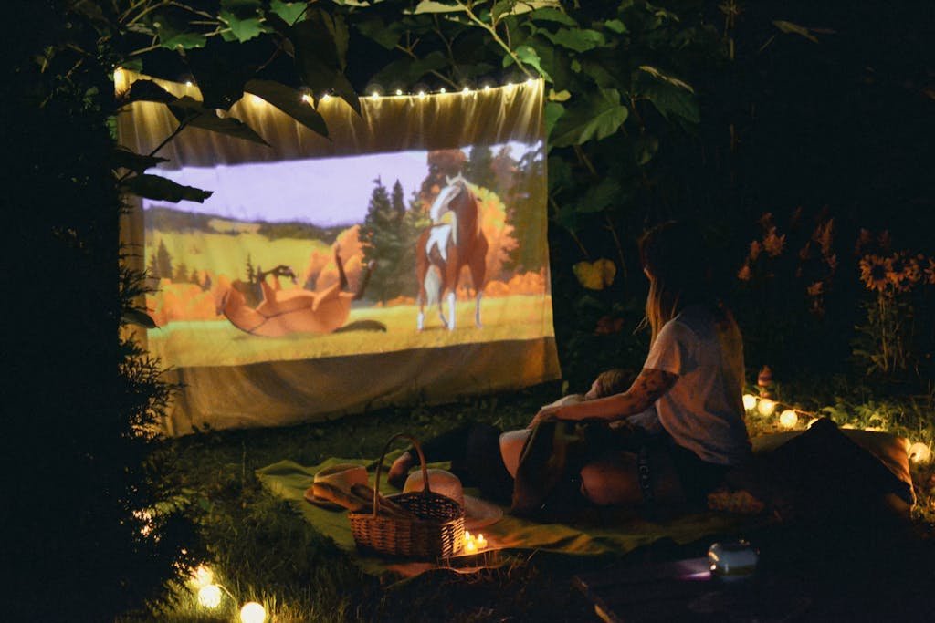 Enjoy a cozy outdoor movie night with a projector and picnic setup under the night sky.