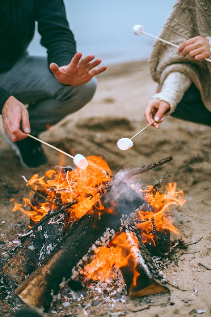 Enjoying a cozy beach bonfire and roasting marshmallows with friends.