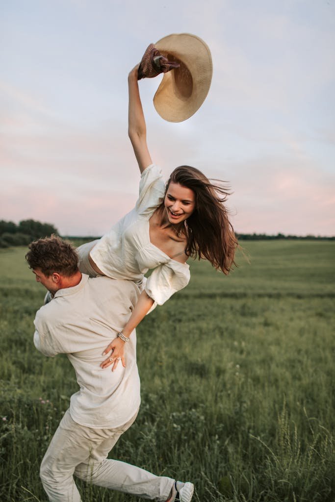 Happy couple enjoying a playful moment in a green field at sunset.