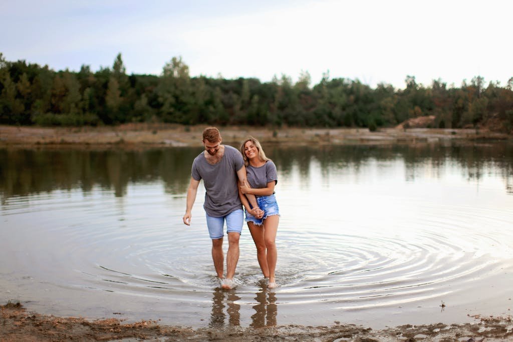 Happy couple walking together by a serene lake, expressing love and joy.