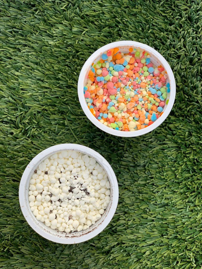 Overhead view of colorful and white ice cream in bowls on a grass lawn.