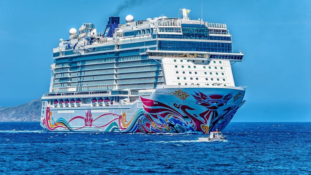 A colorful cruise ship sailing on the open sea under a clear blue sky. Ideal for tourism and travel themes.