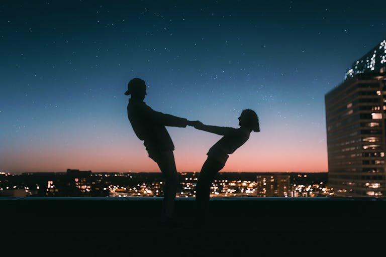 A couple silhouetted against a starry sky on a rooftop in Minneapolis at sunset.