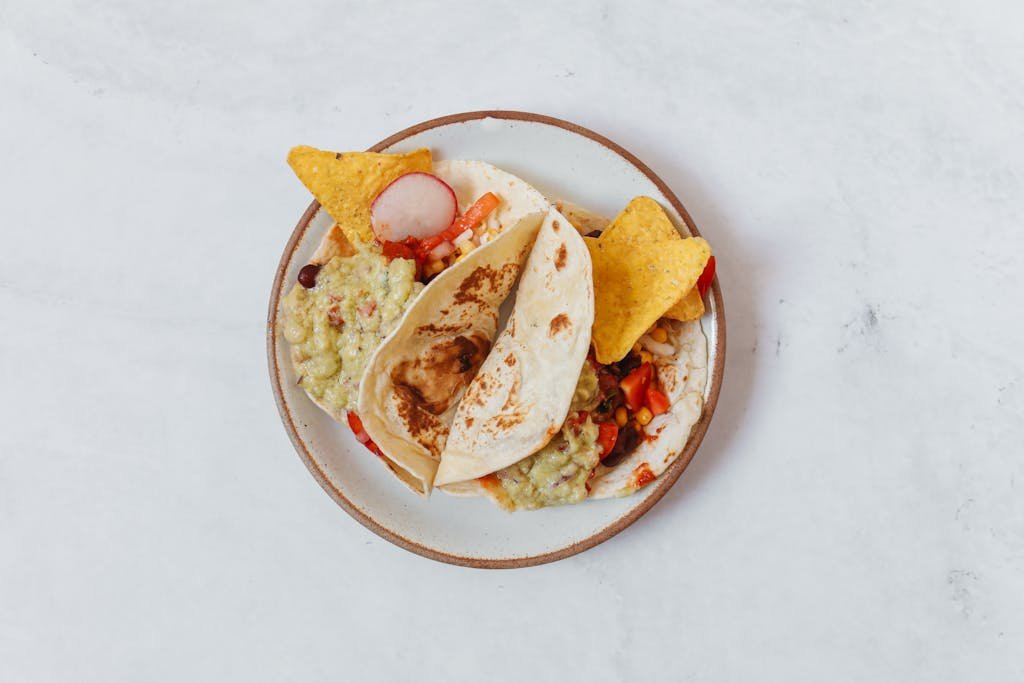 A delectable plate of Mexican tacos served with fresh guacamole and tortilla chips.