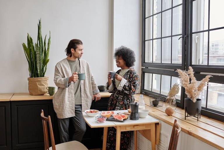 A joyful couple enjoys a morning coffee and healthy breakfast of grapefruit in their cozy apartment.