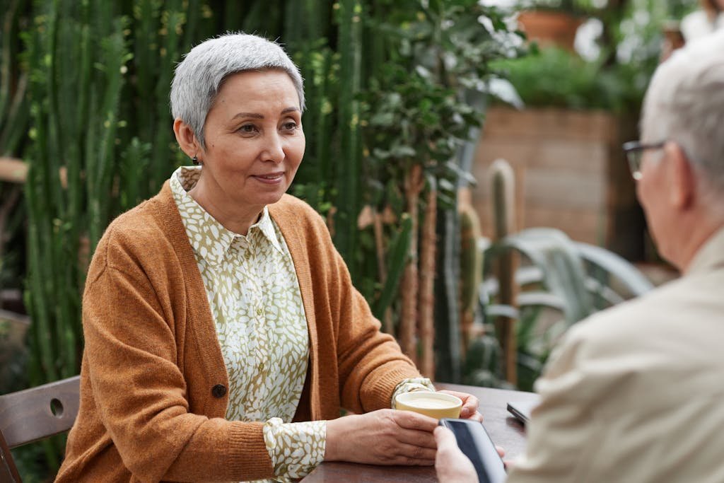 A senior couple enjoying coffee and conversation in a lush garden setting