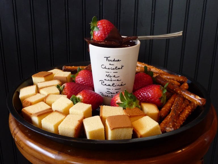 A tray of delicious chocolate fondue with strawberries, cake, and pretzels, offering a tempting dessert option.