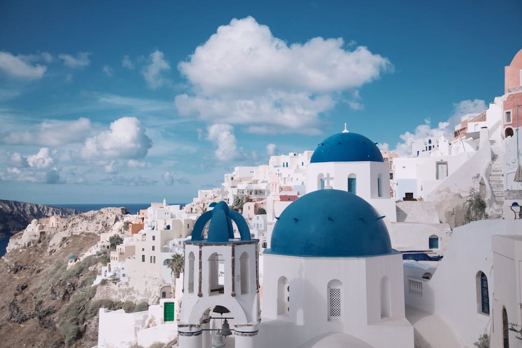 Breathtaking view of Oia's iconic blue-domed churches against a vibrant sky in Santorini, Greece.