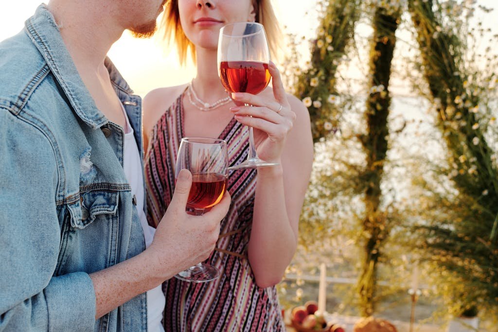 Couple toasting with wine glasses in a romantic outdoor setting at sunset.