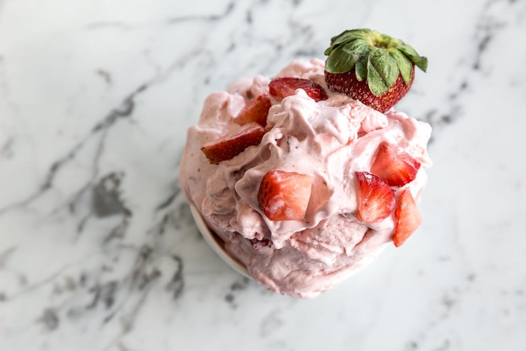 Creamy strawberry mousse served on a marble counter, topped with fresh strawberry slices.