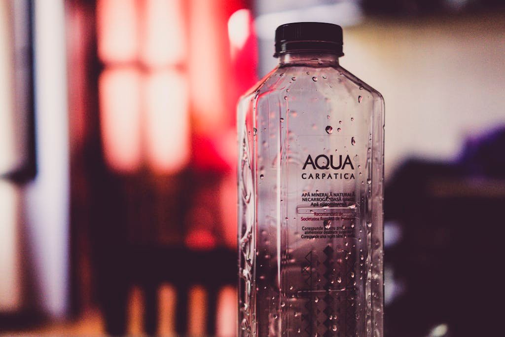 Detailed view of an Aqua Carpatica water bottle with droplets and blurred background.