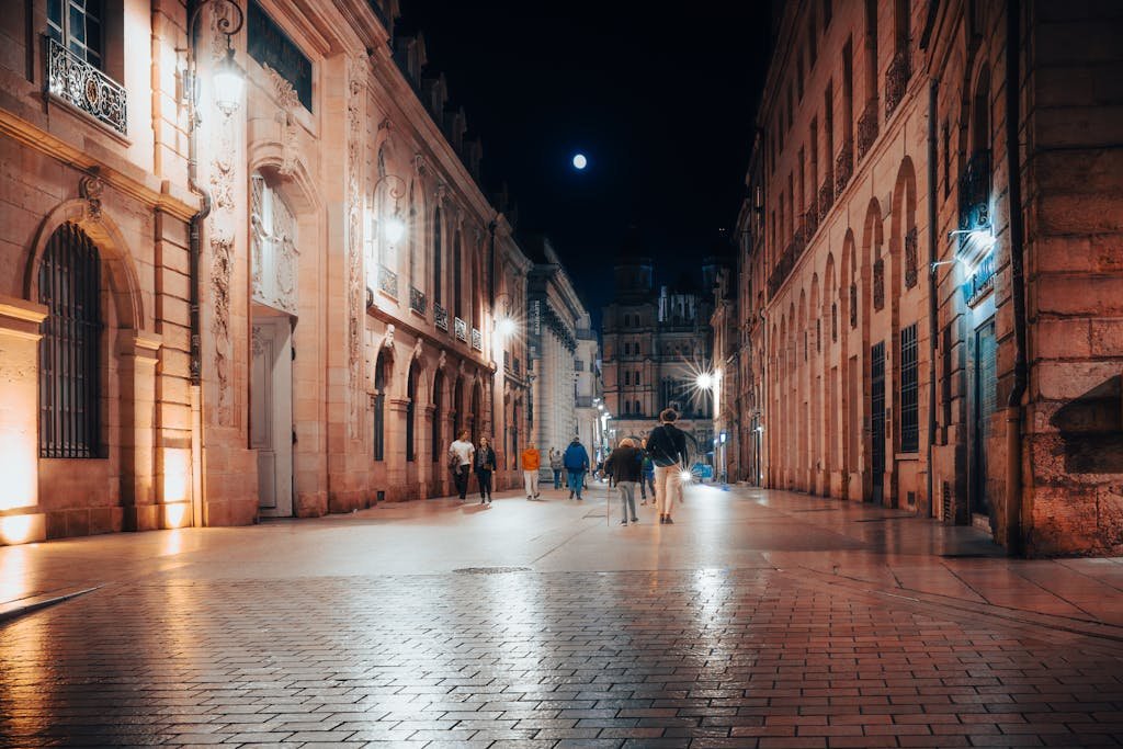 Discover the charm of Dijon at night with illuminated architecture and lively street scenes.