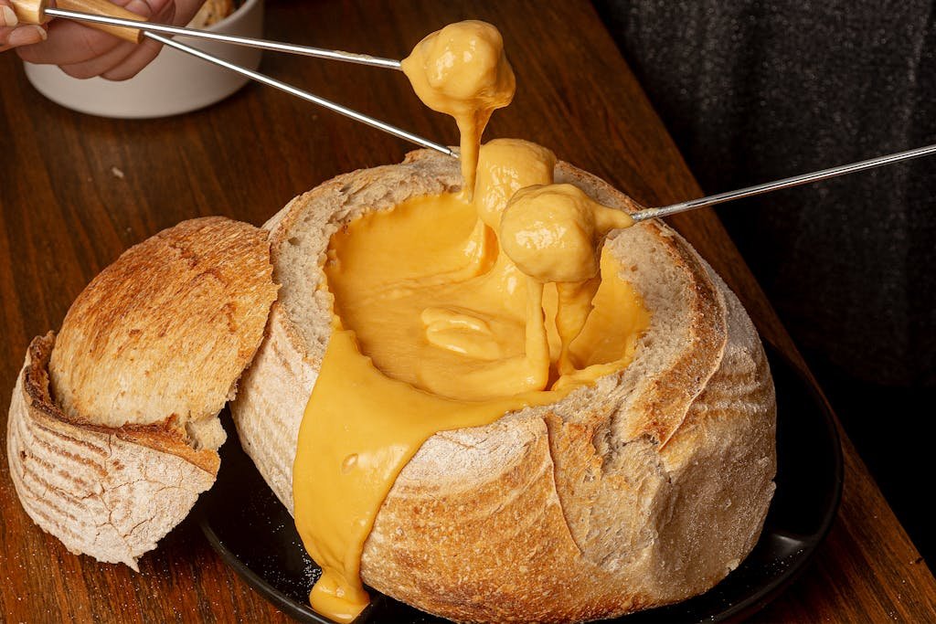 Scrumptious cheese fondue in a rustic bread bowl on a wooden table.