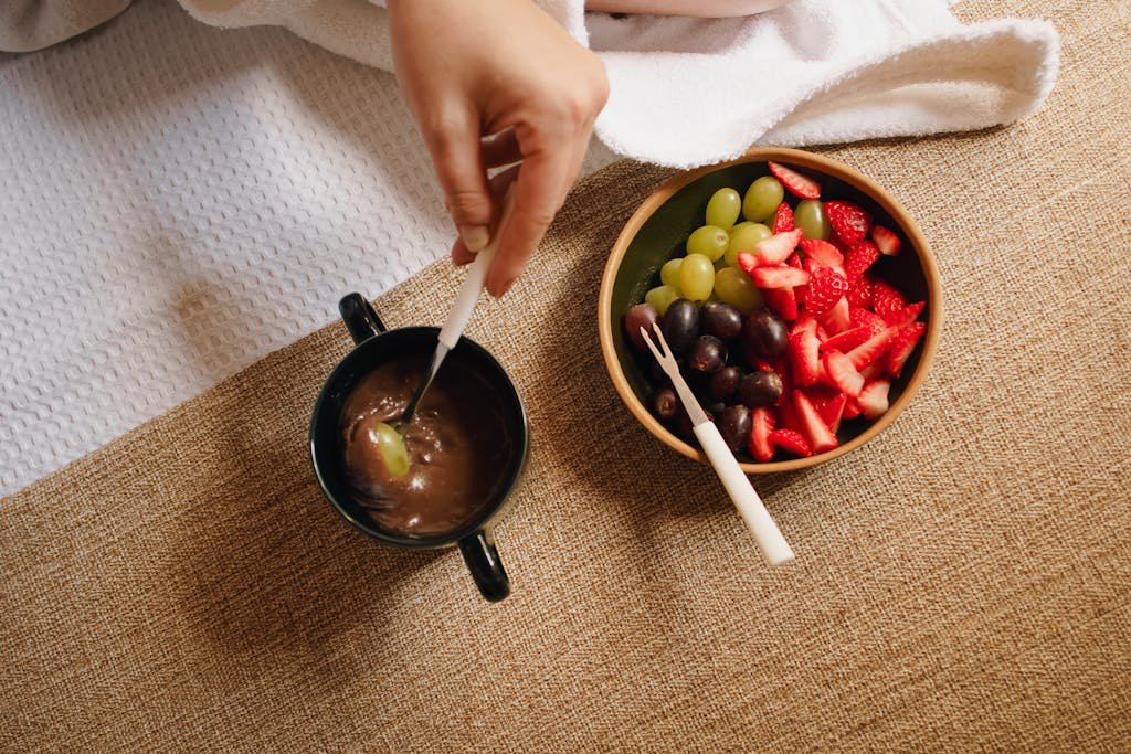 Top view of a delicious fruit and chocolate fondue setup with strawberries, grapes, and dipping cup.