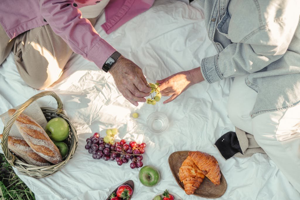 Top view of a relaxing picnic with fresh fruits, bread, and croissants.