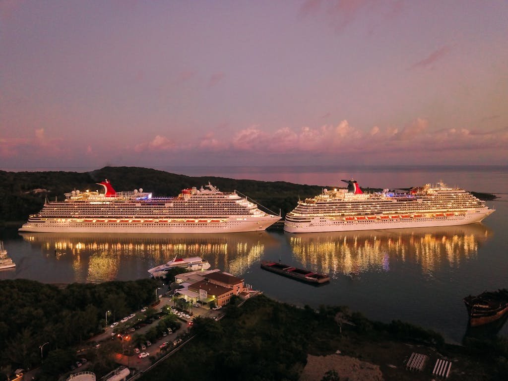 Two illuminated cruise ships docked at Coxen Hole, Honduras during twilight.