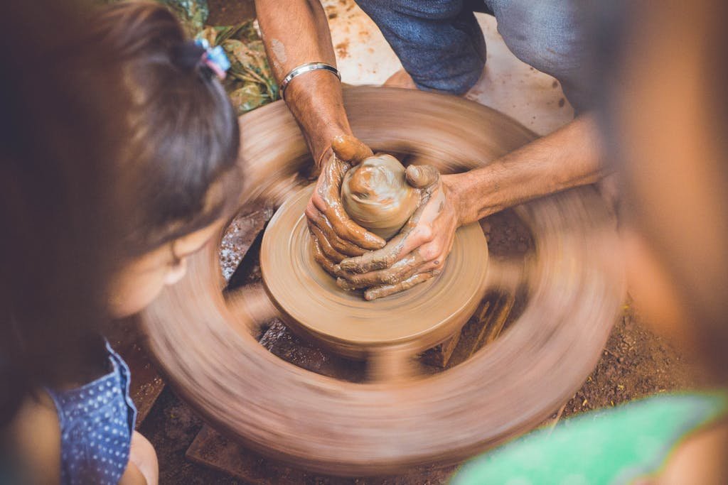 The Secret to Sticking With Weekly Date Nights 6 Close-up of hands shaping clay on a pottery wheel, capturing the artistry of crafting.