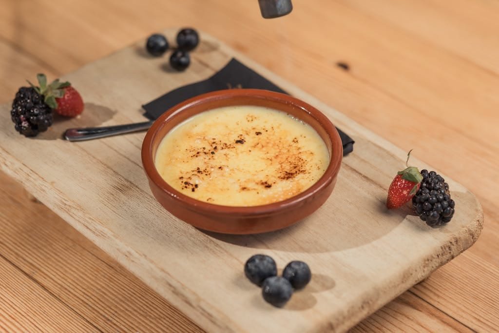Delicious creme brulee served with fresh berries on a wooden board.