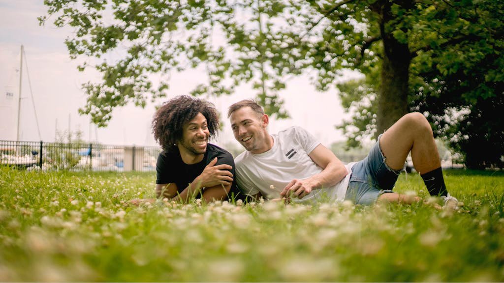 Two men enjoying a sunny day at a Chicago park, portraying love and relaxation.
